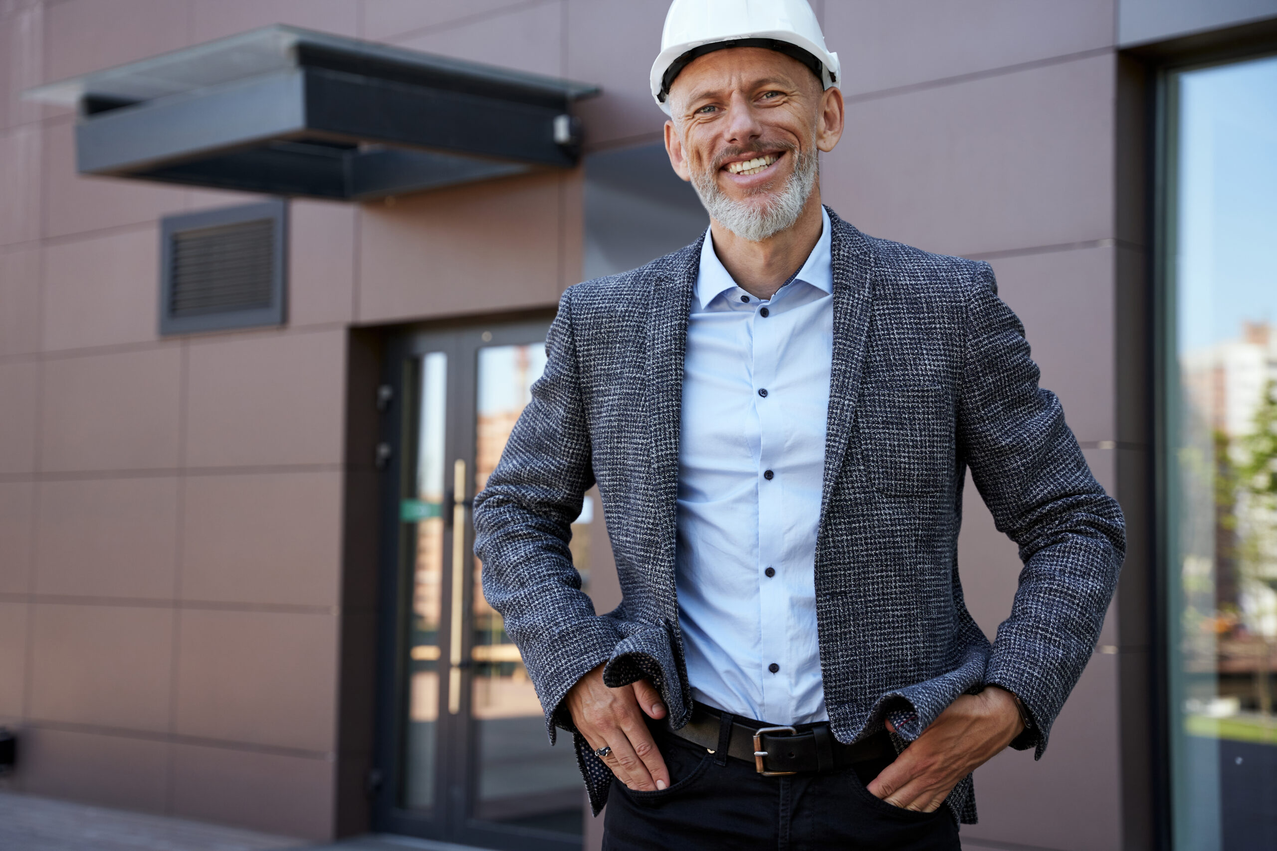 Creative and Successful. Happy mature architect, engineer manager wearing helmet smiling at camera, standing outdoors, planning new project